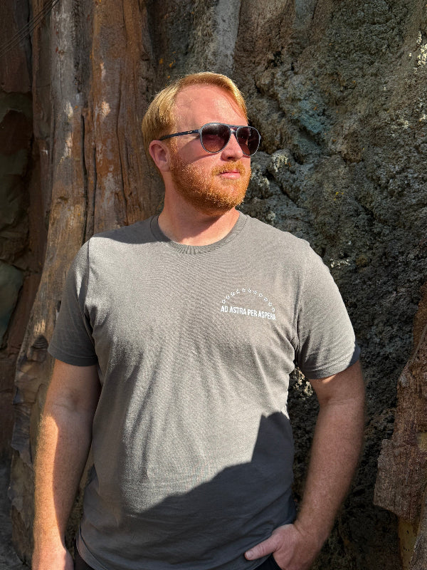 Man wearing sunglasses and a gray t-shirt lying on a rock surface