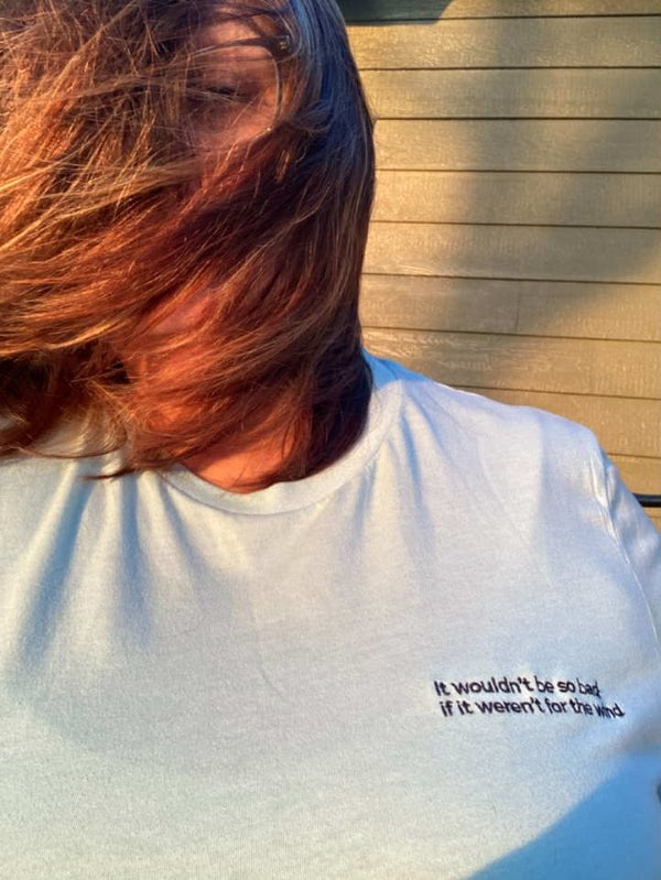 Person wearing a white t-shirt with text outdoors